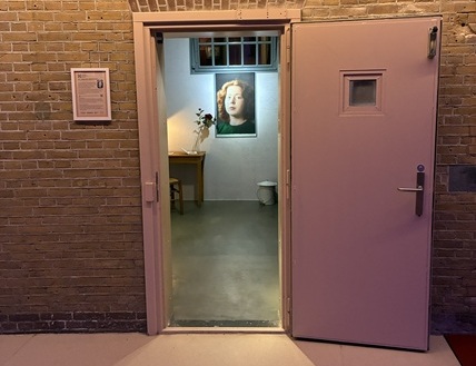In deze cel, dicht bij de plek waar verzetsvrouw Hannie Schaft (1920 – 1945) tijdens de Tweede Wereldoorlog gevangen zat, wordt haar verhaal opnieuw tot leven gebracht. Deze ruimte verbeeldt haar laatste dagen, haar rol in het verzet, haar moed en haar dood. Op de plek waar Hannie Schaft angstige uren doorbracht, ontstaat nu een moment van reflectie en bewustwording. Door middel van beeld, geluid en de inrichting van de ruimte worden bezoekers uitgenodigd stil te staan bij haar verhaal en bij de vraag: hoe Hannie ben jij?